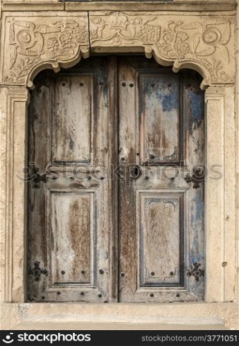 Old aged weathered wooden rural church door on stone frame