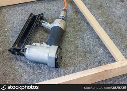 Old air nailer with wooden frame on table