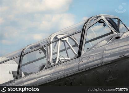 Old airplane cabin against a blue sky. Classic aircraft with silver and riveted fuselage