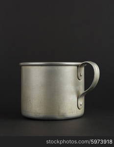 Old aluminum mug on a black background