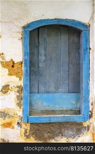 Old and deteriorated wooden window painted in blue in the historic city of Paraty on the south coast of the state of Rio de Janeiro. Old and deteriorated wooden window painted in blue