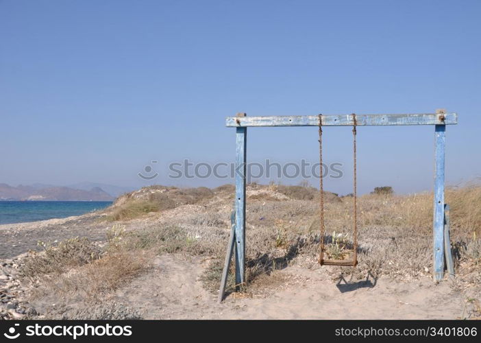 old and rusty swing on a Greek beach