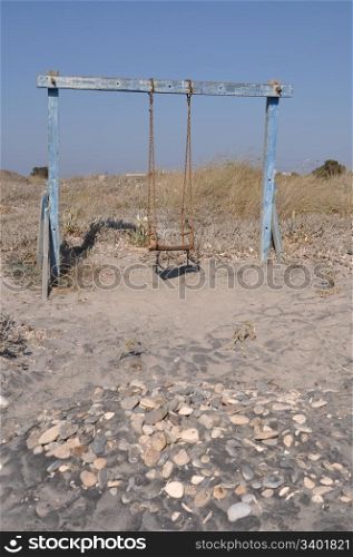 old and rusty swing on a Greek beach