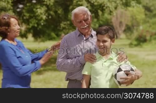 Old and young people leisure, seniors and kids in family, generations with child and retired persons. Sport activity, child playing football game, soccer in park. Happy elderly man, woman, boy smiling