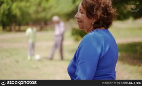 Old and young people together, seniors and children in family, generations with child and elderly persons. Sport activity, boy playing football game with grandpa, soccer in park. Happy grandma smiling