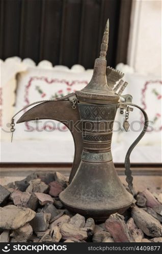 Old Arabic metal pitcher on hot coals. Old Arabic metal pitcher