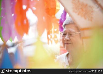 old asian elder elderly senior woman praying with paper lantern