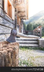 Old axe attached to a tree trunk, alpine hut