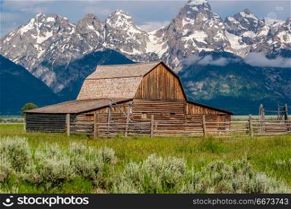 Old barn in Grand Teton Mountains . Old mormon barn in Grand Teton Mountains with low clouds. Grand Teton National Park, Wyoming, USA.