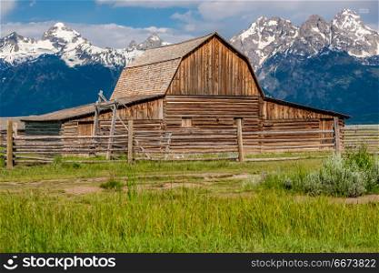 Old barn in Grand Teton Mountains . Old mormon barn in Grand Teton Mountains with low clouds. Grand Teton National Park, Wyoming, USA.