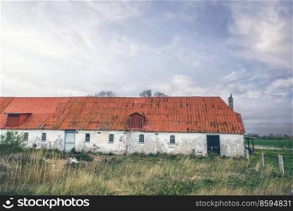 Old barn made of stone in a rural countryside scenery with tall grass