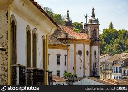 Old baroque church among the houses, balconies and windows of the city of Ouro Preto in Minas Gerais. Old baroque church among the houses