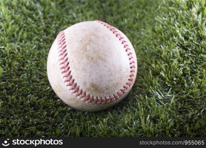 Old Baseball in closeup over synthetic grass, horizontal image