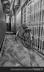 Old bicycle in black and white. Bike left at the fence on the street