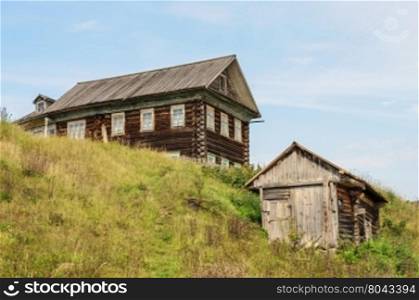 Old big log house and a shed in russian village, Vologda region. Summer day