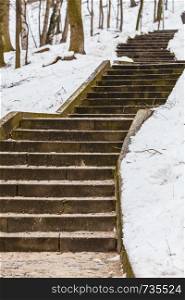 Old big stairs in centre of park during cold snowy winter weather. Snow on ground.. Stairs in winter public park