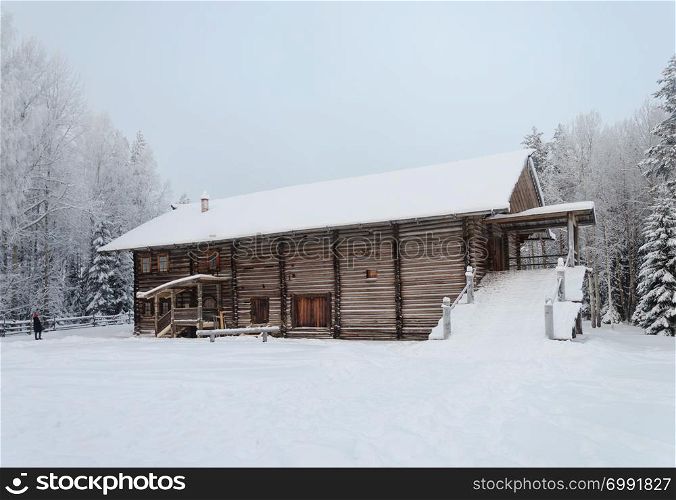 Old big wooden peasant house with yard in Northern Russia. Open air museum Malye Korely near Arkhangelsk, snowy winter day.