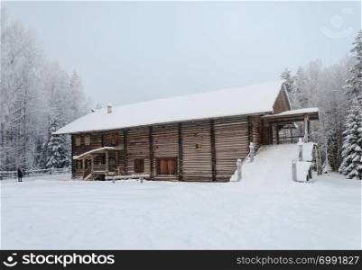 Old big wooden peasant house with yard in Northern Russia. Open air museum Malye Korely near Arkhangelsk, snowy winter day.