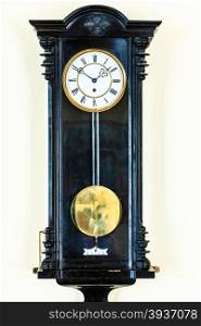 old big wooden pendulum clock hanging on wall