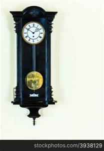 old big wooden pendulum clock hanging on wall