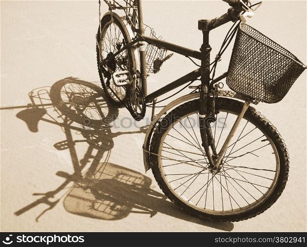 Old bike reflect on sand surface under sunshine on day