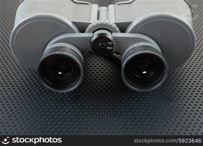 Old binoculars on a metallic background with perforation of round holes
