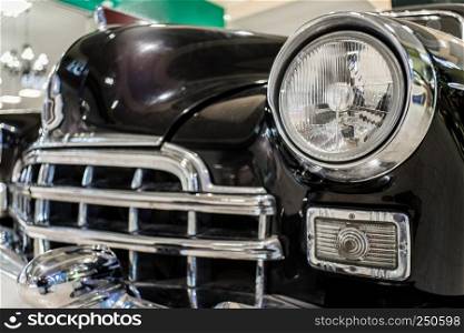 Old black car close up with grille and headlamp on exhibition