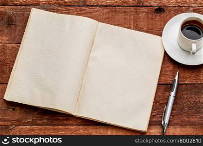 old blank notebook opened on a red barn wood table with a cup of coffee