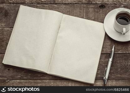 old blank notebook opened on a rustic barn wood table with a cup of coffee, sepia toned