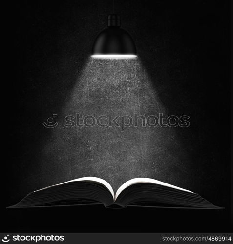 Old book in darkness. Opened book with light on pages on black background