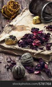 old book is strewn with the tea leaves on wooden background,tinted in vintage style