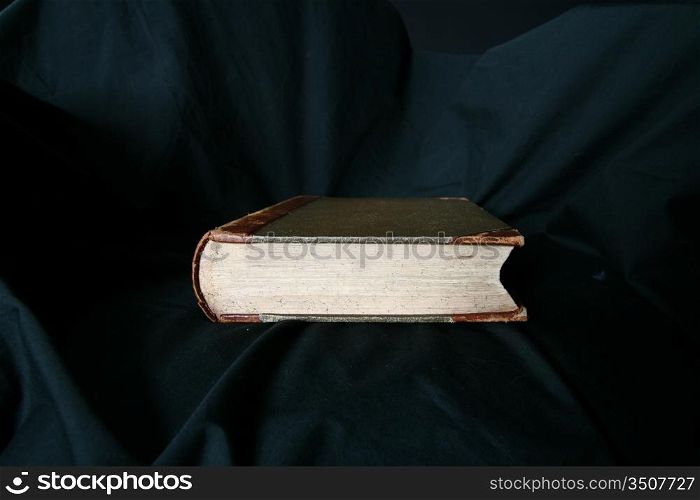 old book laying on black drapery