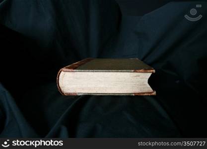 old book laying on black drapery