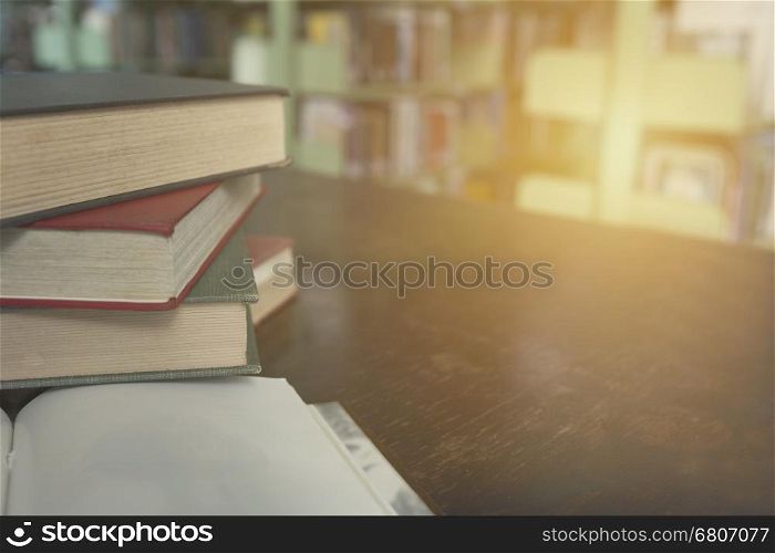 old book stack on wooden table with blur library background