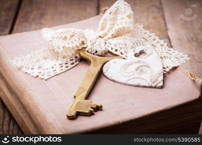 Old book with vintage key and wooden heart, memories concept