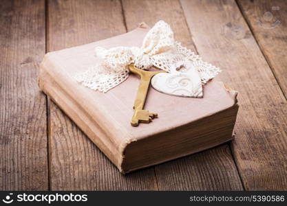 Old book with vintage key and wooden heart, memories concept