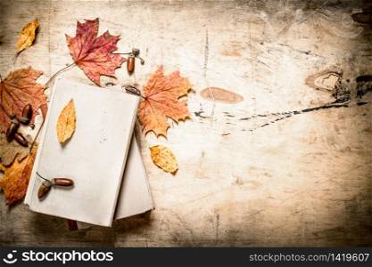 Old books and autumn leaves. On wooden background.. Old books and autumn leaves.