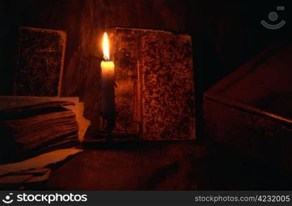 Old books ,box and candle isolated on dark