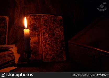 Old books in dark room with candle