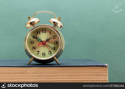 old books on a wooden shelf and alarm clock