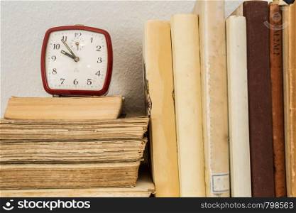old books on wooden shelf with little clock vintage. old books on wooden shelf with little clock