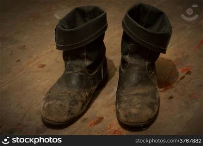 Old Boots - distressed and dirty, on a the same wooden floor