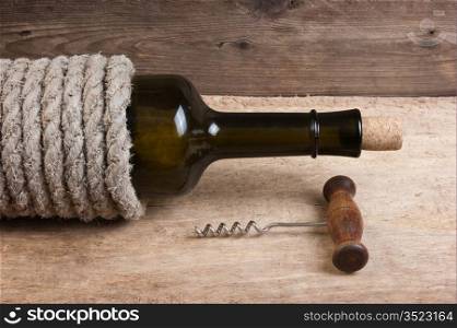 Old bottle of wine and corkscrew on the board
