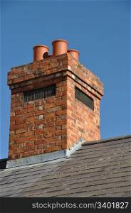 old brick chimney on black tile roof (blue sky)