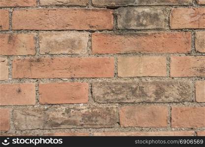 Old brick wall with cracks and scratches. Brick wall background. Distressed wall with broken bricks texture. House facade