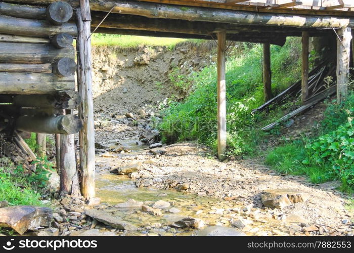 Old bridge over the forest stream in hot summer day