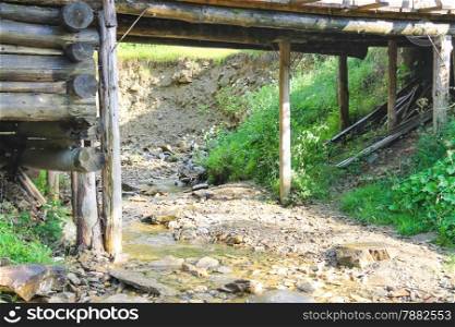 Old bridge over the forest stream in hot summer day