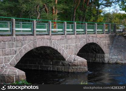 Old bridge with arches over a small river in a green landscape