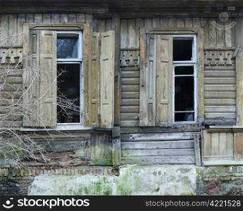 Old broken house in spring, damaged windows and sun-blinds