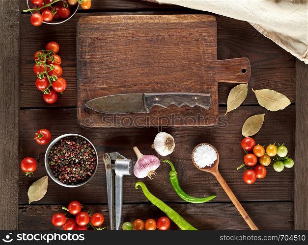 old brown empty kitchen cutting and fresh red cherry tomatoes with green chili peppers on the table, top view